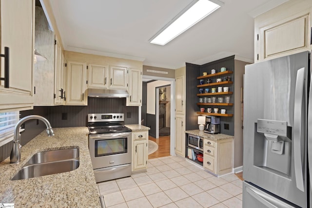 kitchen featuring appliances with stainless steel finishes, a sink, open shelves, light tile patterned floors, and light stone counters