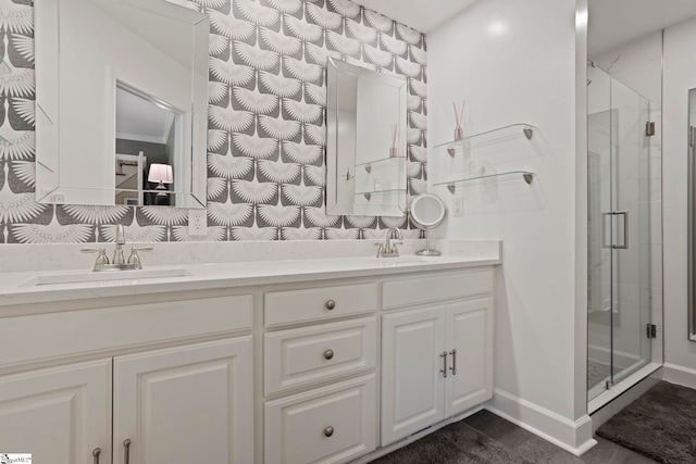bathroom with a stall shower, double vanity, and baseboards