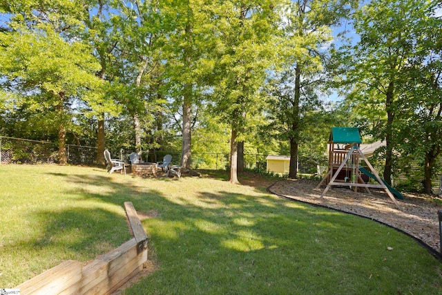 view of yard with a playground, a fire pit, and view of scattered trees