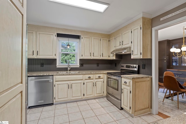 kitchen with appliances with stainless steel finishes, under cabinet range hood, a sink, ornamental molding, and light tile patterned floors