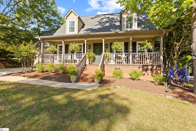 cape cod home with covered porch, a front lawn, roof with shingles, and stairs