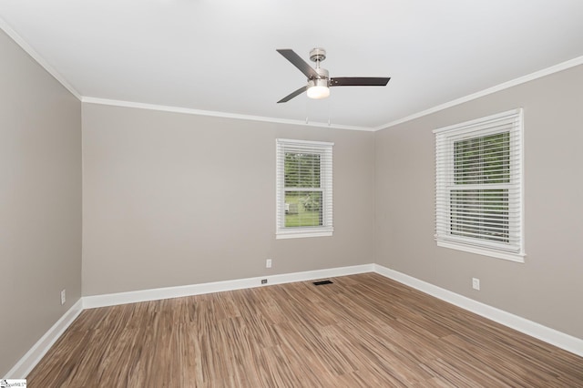 spare room with ornamental molding, baseboards, wood finished floors, and a ceiling fan