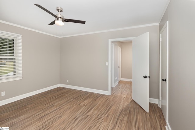 empty room featuring a ceiling fan, light wood finished floors, baseboards, and ornamental molding