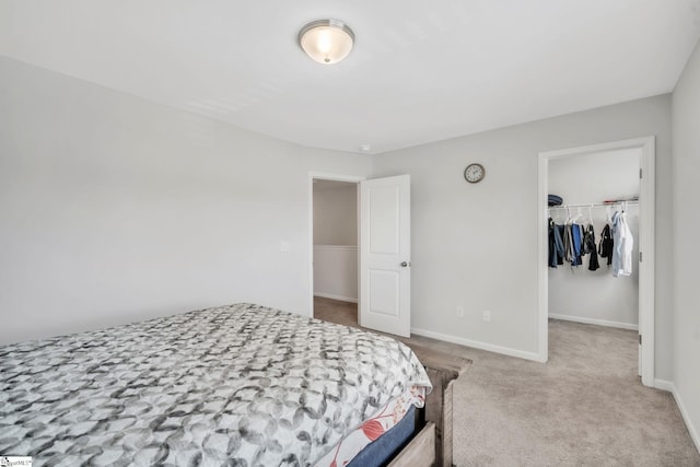 bedroom featuring carpet floors, a walk in closet, a closet, and baseboards