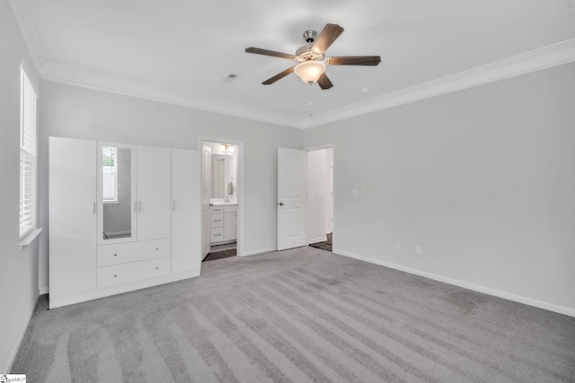 unfurnished bedroom featuring ornamental molding, carpet floors, baseboards, ensuite bath, and a ceiling fan