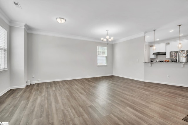 unfurnished living room featuring a chandelier, crown molding, wood finished floors, recessed lighting, and baseboards
