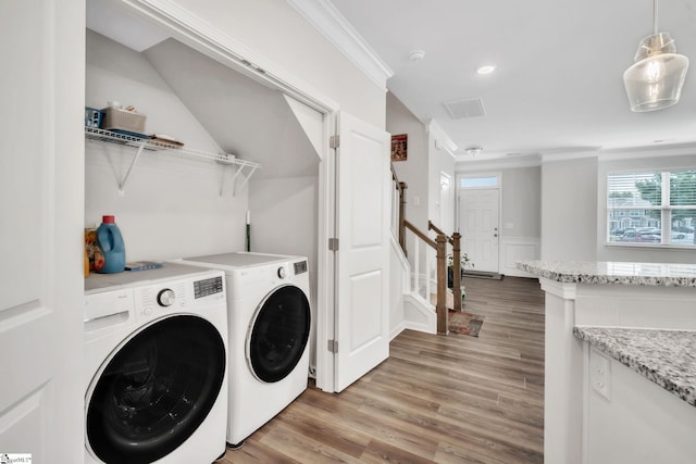 clothes washing area with light wood finished floors, washer and clothes dryer, ornamental molding, and recessed lighting