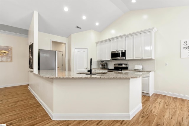 kitchen featuring appliances with stainless steel finishes, light wood-style floors, light stone countertops, a sink, and recessed lighting