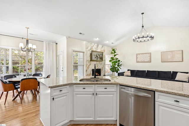kitchen with dishwasher, a chandelier, a sink, a fireplace, and open floor plan