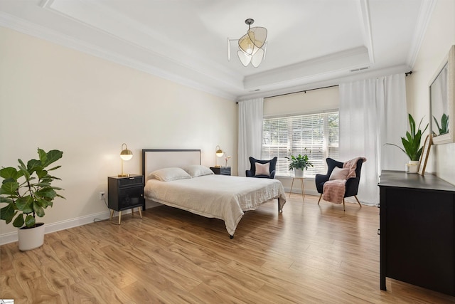 bedroom with a tray ceiling, light wood-style flooring, crown molding, and baseboards