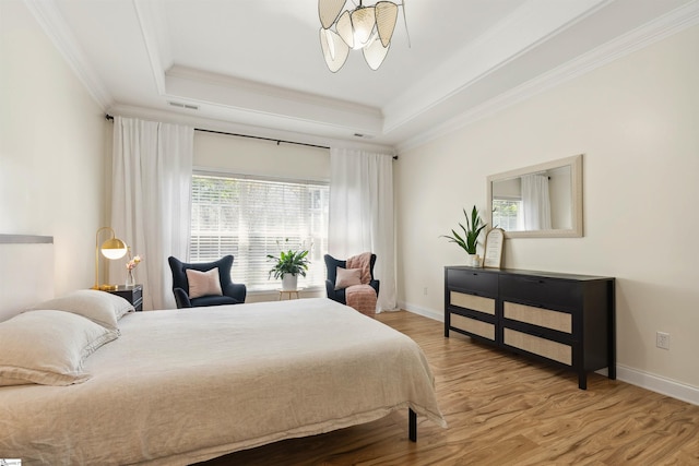 bedroom with crown molding, wood finished floors, a raised ceiling, and baseboards