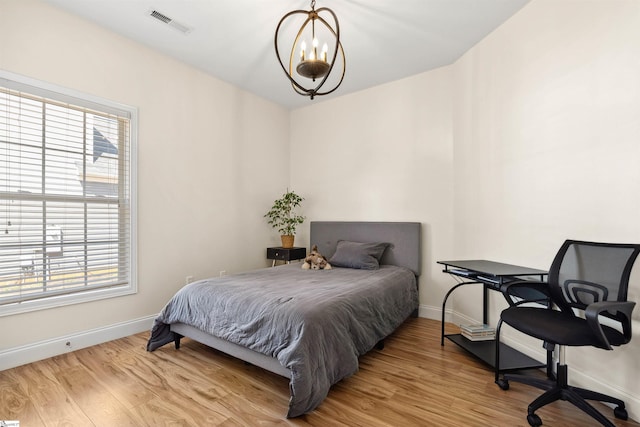 bedroom with baseboards, multiple windows, a chandelier, and light wood finished floors