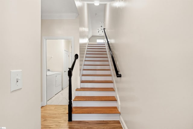stairs featuring washing machine and dryer, crown molding, baseboards, and wood finished floors