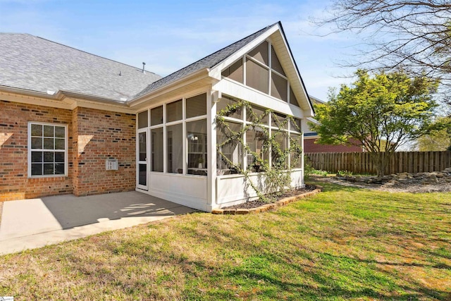 rear view of property with a sunroom, brick siding, a shingled roof, and a patio