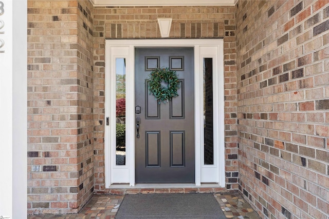 view of exterior entry featuring brick siding