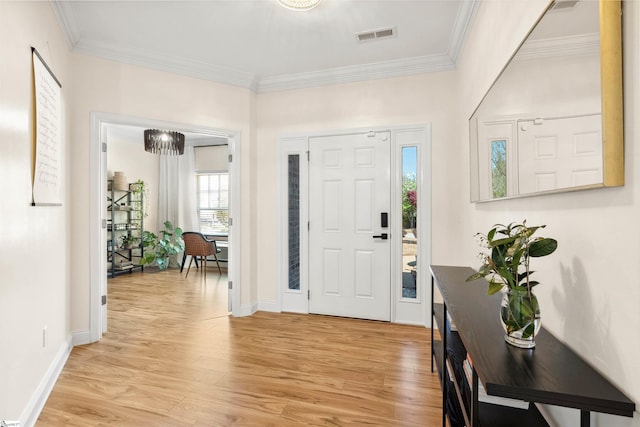 entryway with light wood-style flooring, ornamental molding, and baseboards