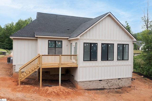 rear view of house with a shingled roof, a wooden deck, board and batten siding, crawl space, and stairs