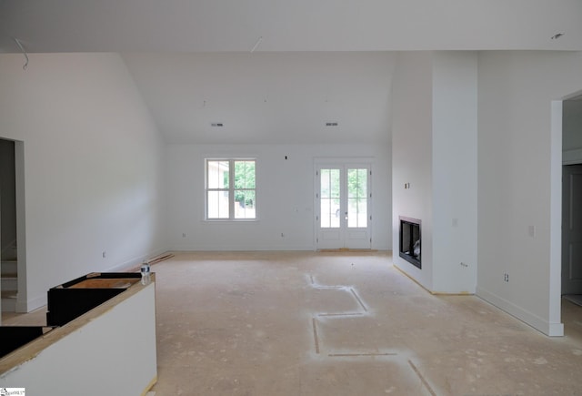 unfurnished living room featuring a glass covered fireplace, lofted ceiling, and baseboards