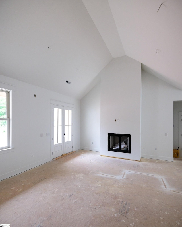 unfurnished living room featuring healthy amount of natural light, vaulted ceiling, and a glass covered fireplace