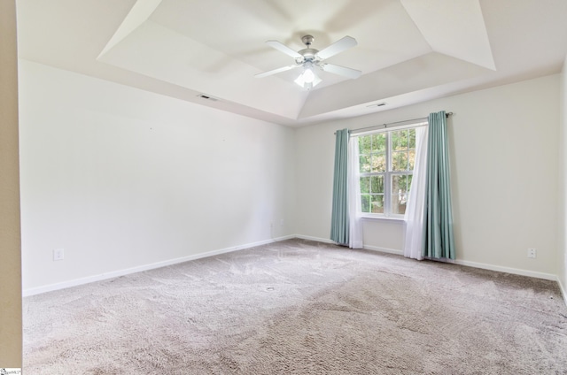 unfurnished room with a tray ceiling, ceiling fan, carpet, and baseboards