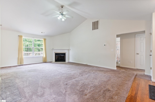 unfurnished living room with a ceiling fan, a fireplace with flush hearth, baseboards, carpet flooring, and high vaulted ceiling