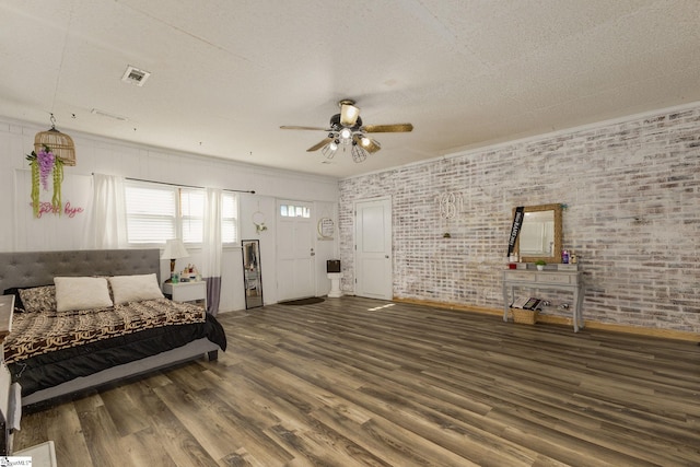 living area featuring wood finished floors, ceiling fan, baseboards, brick wall, and a textured ceiling