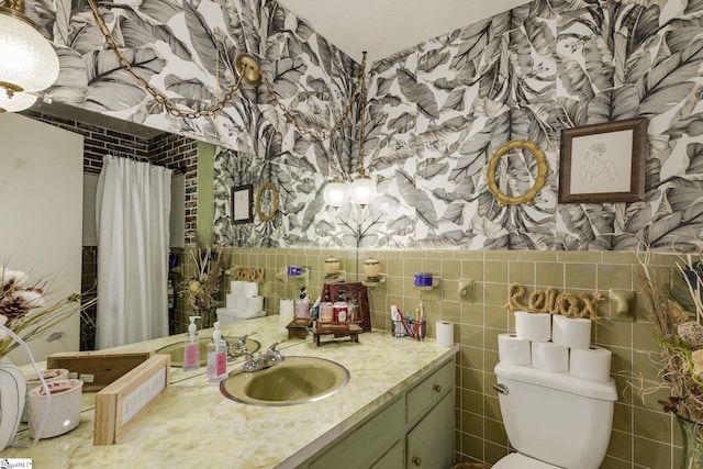 bathroom with wallpapered walls, toilet, vanity, and tile walls