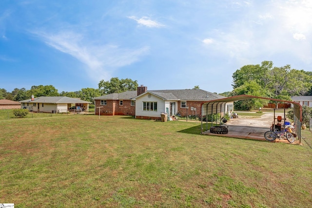 back of house with a carport, a yard, brick siding, and a chimney