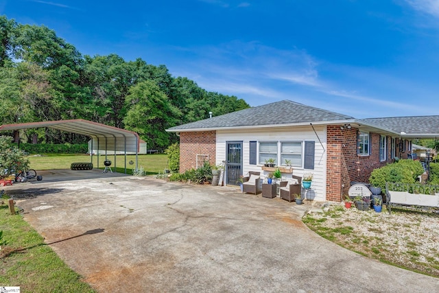 view of home's exterior with brick siding, a detached carport, a yard, and a shingled roof