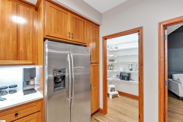 kitchen featuring stainless steel fridge with ice dispenser, light wood-style flooring, light countertops, and brown cabinets