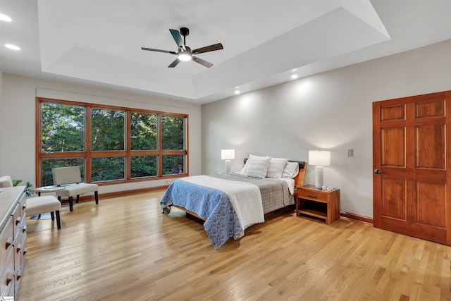 bedroom featuring a tray ceiling, light wood-style flooring, recessed lighting, baseboards, and ceiling fan