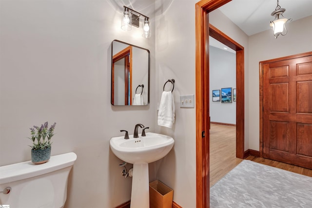 bathroom with wood finished floors, toilet, and baseboards
