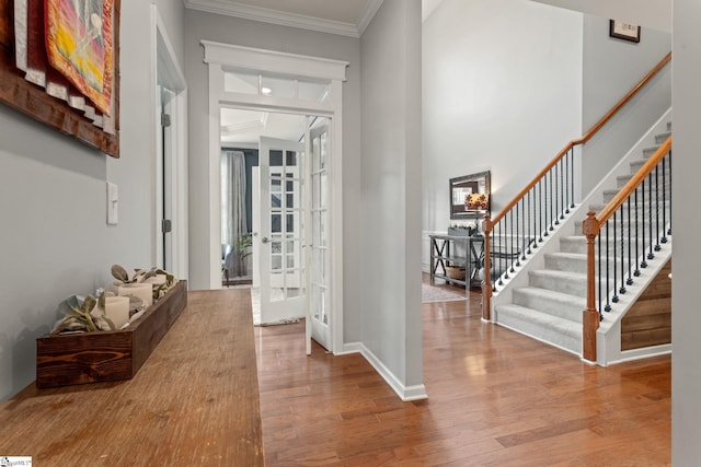 entrance foyer with stairway, wood finished floors, ornamental molding, french doors, and baseboards