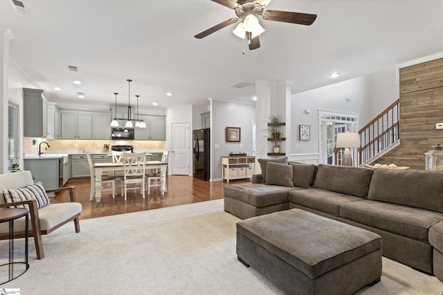 carpeted living area featuring a ceiling fan, ornamental molding, recessed lighting, stairway, and wood finished floors