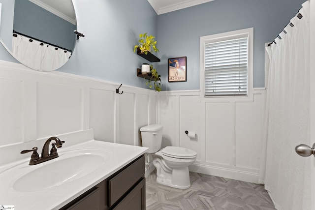bathroom with a decorative wall, wainscoting, vanity, toilet, and ornamental molding