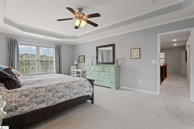 bedroom featuring a tray ceiling, light carpet, crown molding, baseboards, and ceiling fan