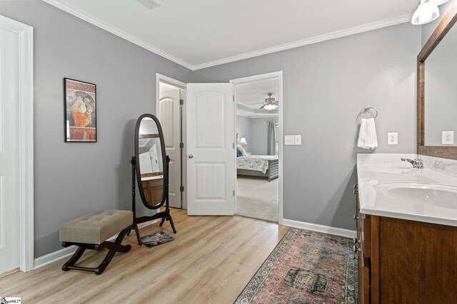 bathroom with wood finished floors, connected bathroom, double vanity, baseboards, and crown molding