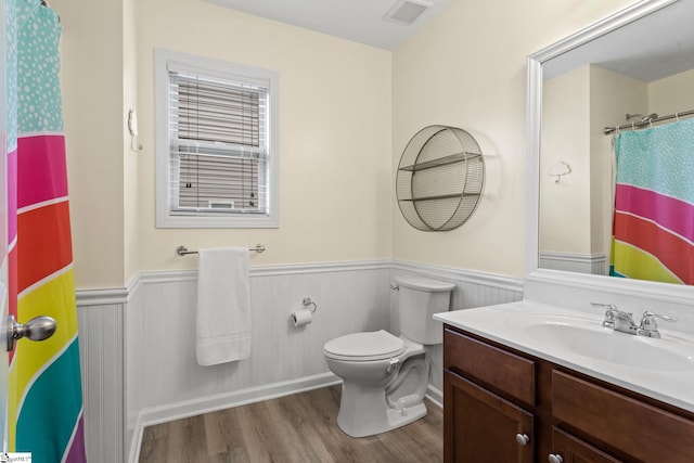 bathroom with wainscoting, wood finished floors, toilet, vanity, and a shower with shower curtain