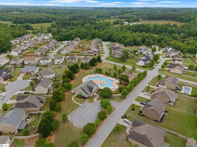 view of property location with nearby suburban area, a pool area, and a heavily wooded area