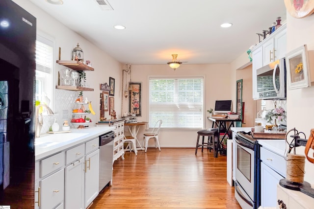 111 Woodvale Ave, Fountain Inn, SC 29644 - kitchen with appliances with stainless steel finishes, a sink, open shelves, light wood-style flooring, and light countertops