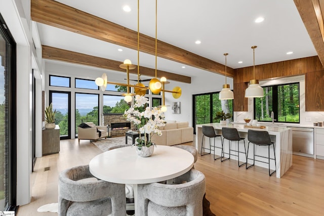 dining space with light wood finished floors, recessed lighting, and beam ceiling