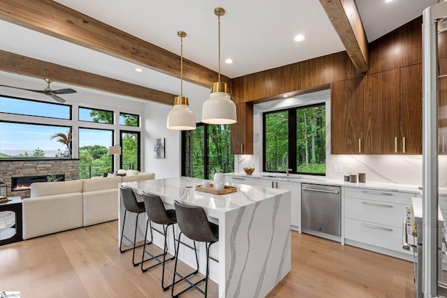 kitchen with dishwasher, beamed ceiling, modern cabinets, plenty of natural light, and a kitchen breakfast bar