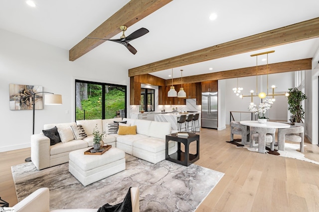 living area with beamed ceiling, light wood finished floors, a ceiling fan, recessed lighting, and a chandelier
