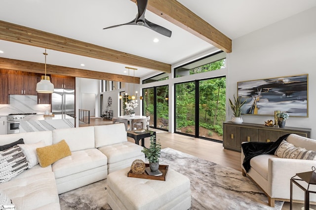 living area with beam ceiling, ceiling fan, light wood-style flooring, recessed lighting, and a chandelier