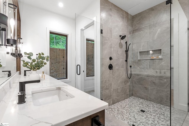 bathroom featuring a tile shower, double vanity, and recessed lighting