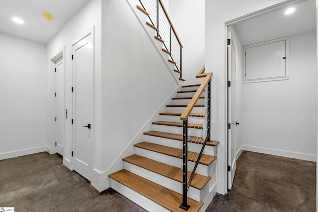 stairs with finished concrete flooring, baseboards, and recessed lighting