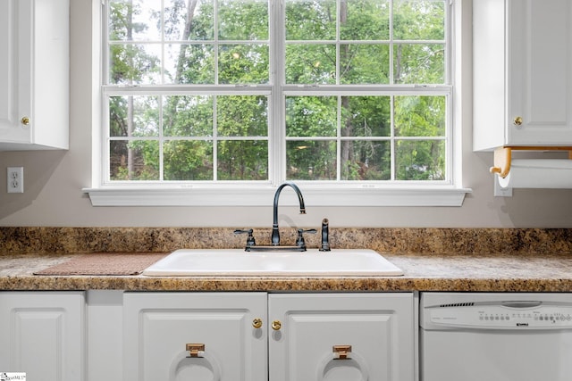 kitchen featuring white dishwasher, a sink, white cabinetry, and healthy amount of natural light