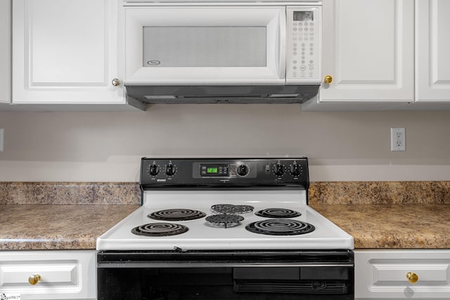 kitchen with black electric range oven, white microwave, and white cabinetry