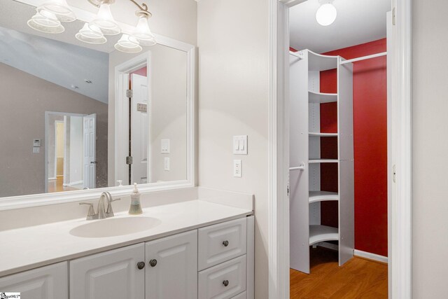 bathroom featuring wood finished floors, vanity, a chandelier, and vaulted ceiling