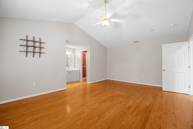 unfurnished bedroom with lofted ceiling, light wood-style floors, baseboards, connected bathroom, and ceiling fan